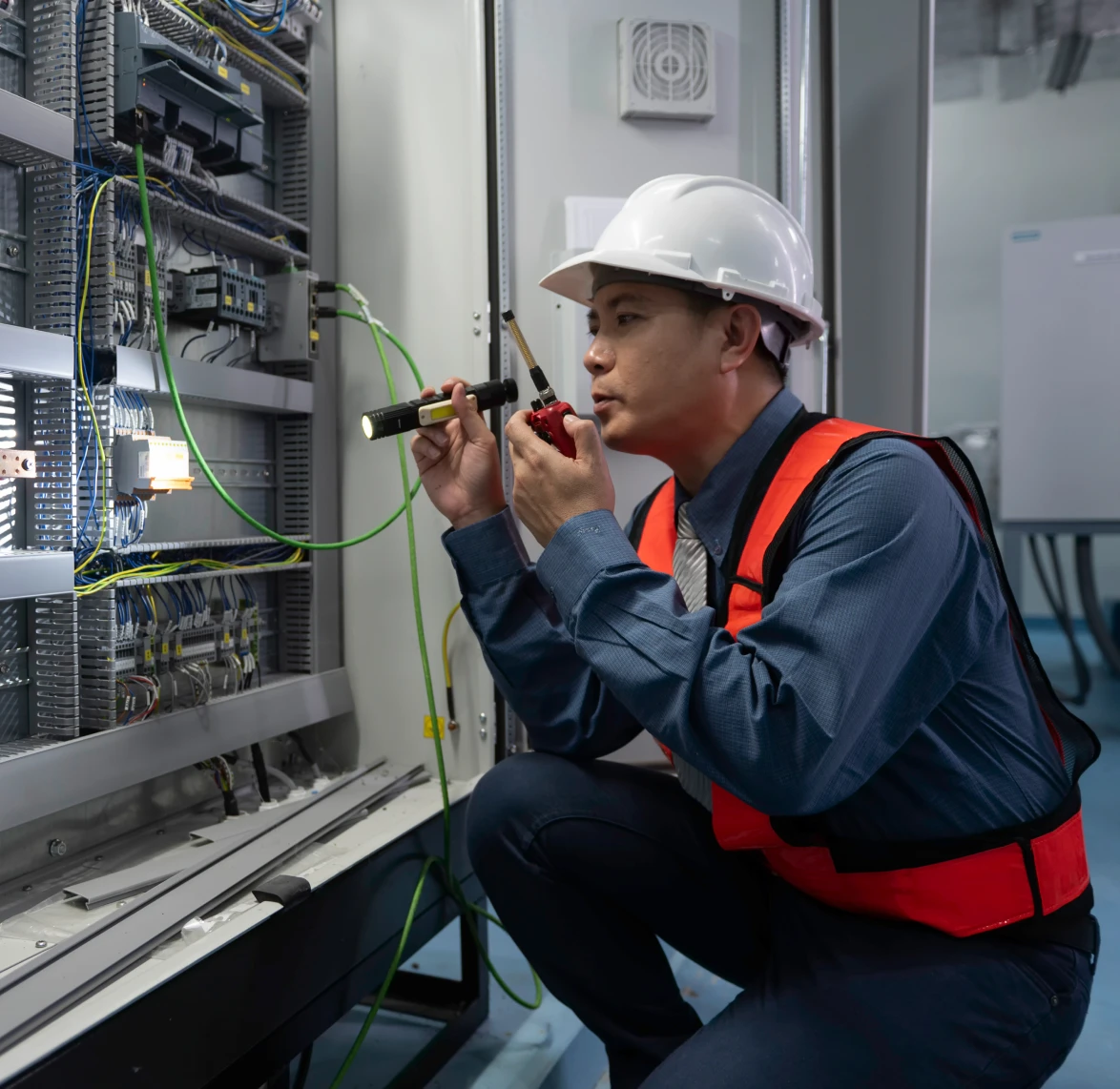 Engineer inspecting electrical panel with flashlight